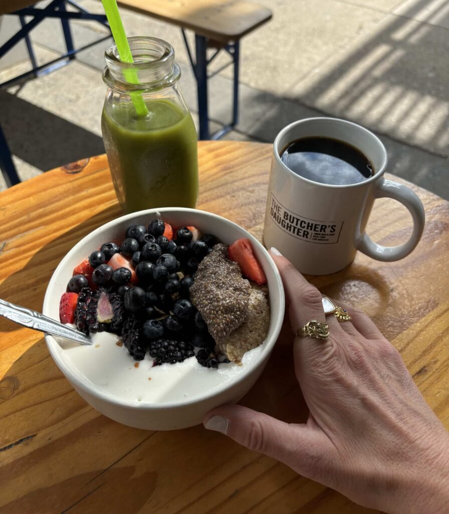 Coconut yogurt and ganola bowl with black coffee and green juice at The Butcher's Daughter, New York.